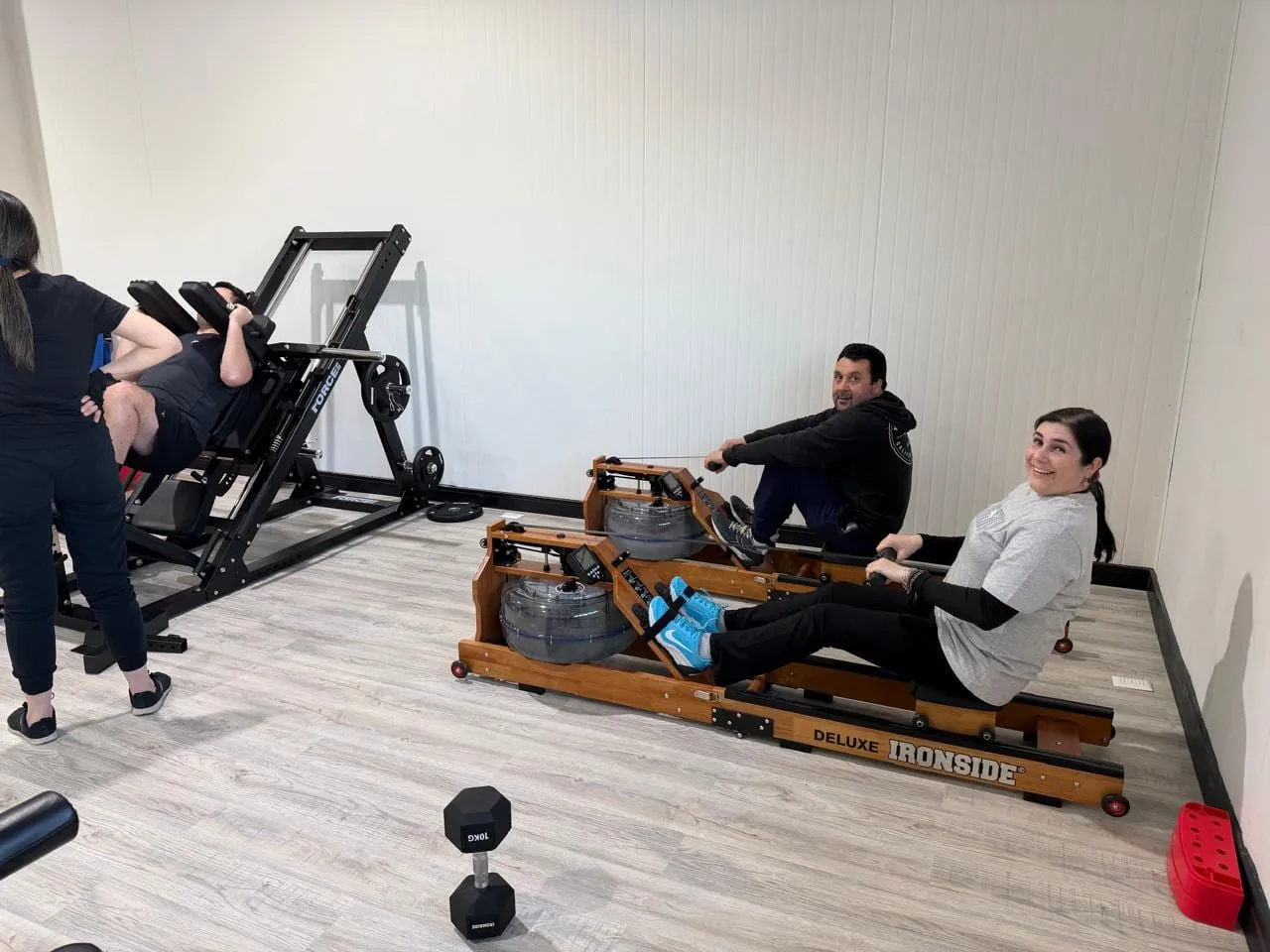 Dos integrantes del equipo en las máquinas de remo del gimnasio